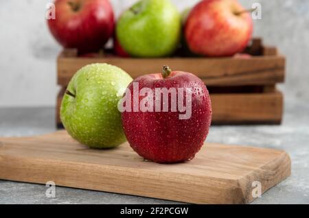 Whole wet green and red apples on wooden cutting board Stock Photo