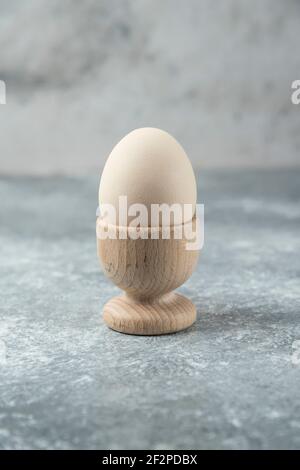 Raw egg in wooden bowl on marble table Stock Photo