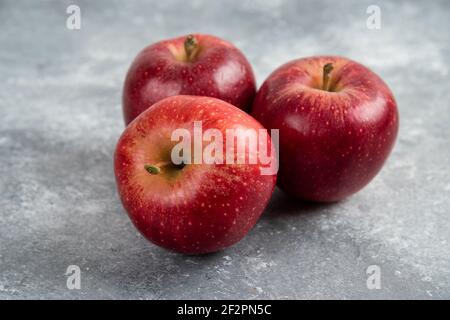 Three ripe red apples placed on marble surface Stock Photo