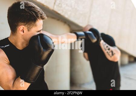 Two men exercising and fighting in outside. Boxer in gloves is training with a coach Stock Photo