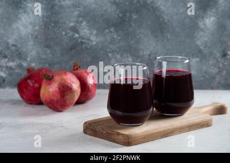 Two glass of a red pomegranate drinking juice on a wooden board Stock Photo