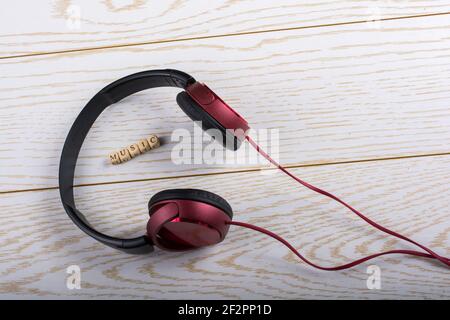 Dice-sized alphabet cubes spelling music and red headphones on wooden background Stock Photo