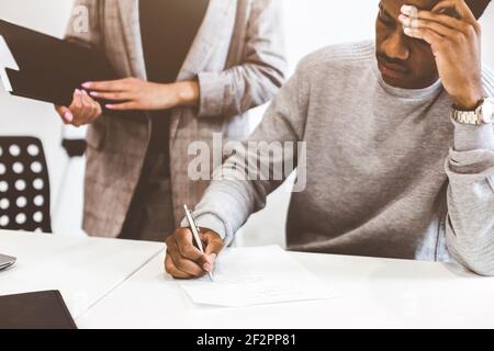 African american man signing contract, black man hand putting signature on official document, biracial clients customers couple make purchase or sign Stock Photo