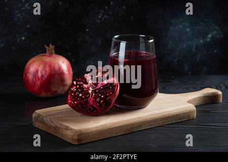 A glass cup of fresh pomegranate juice on a wooden board Stock Photo