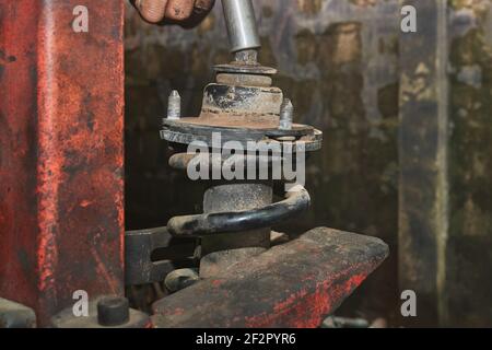 Car Mechanic or Auto Mechanic Loosen Upper Shock Absorber Nut by Wind Block. Shock Absorber Removal by Spring Compressor Tool Stock Photo