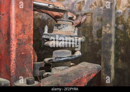 Car Mechanic or Auto Mechanic Loosen Upper Shock Absorber Nut by Wrench and Jaw Locking Pliers. Shock Absorber Removal by Spring Compressor Tool Stock Photo