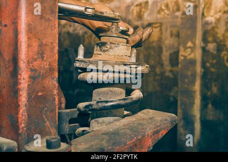 Car Mechanic or Auto Mechanic Loosen Upper Shock Absorber Nut by Wrench and Jaw Locking Pliers. Shock Absorber Removal by Spring Compressor Tool in Vi Stock Photo