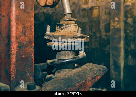 Car Mechanic or Auto Mechanic Loosen Upper Shock Absorber Nut by Wind Block. Shock Absorber Removal by Spring Compressor Tool in Vintage Tone Stock Photo