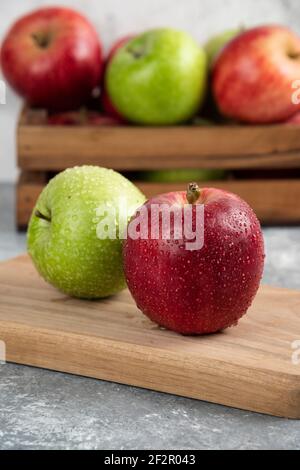 Whole wet green and red apples on wooden cutting board Stock Photo