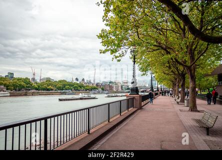 London, UK - April 22 2014: The Queen's Walk in South Bank, by the river Thames. The Skyline of the City of London is in the background. Stock Photo