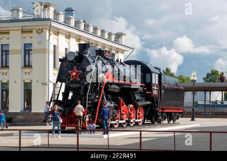 RYBINSK, RUSSIA / August 15, 2020: The building of the railway station and the Soviet steam locomotive L-5270 in front of the railway station building Stock Photo