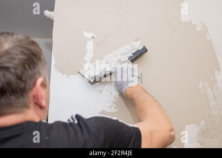 Process putty concrete wall with a metal spatula.process of applying a layer of putty. Renovation of apartments. Repair the walls. Free space for Stock Photo