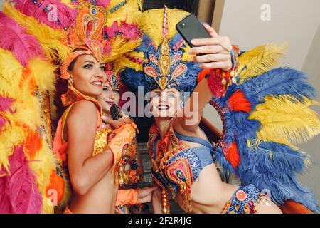 Woman in brazilian samba carnival costume with colorful feathers plumage  with mobile phone take selfie in old entrance with big window Stock Photo -  Alamy