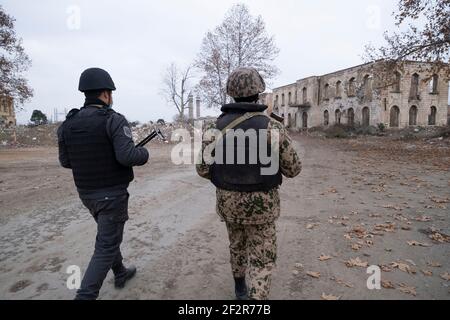 AGDAM, AZERBAIJAN - DECEMBER 14: Azerbaijani servicemen walking through ruined buildings in the town of Agdam which was destroyed by Armenian forces during the First Nagorno-Karabakh War on December 14, 2020 in Agdam, Azerbaijan. The town and its surrounding district were returned to Azerbaijani control as part of an agreement that ended the 2020 Nagorno-Karabakh War. Stock Photo