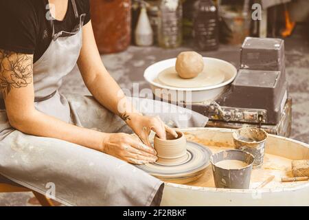 Close-up top view of a female potter makes out of a bricks-like clay large flat plate on a wooden table in a workshop. female potter molding clay with Stock Photo