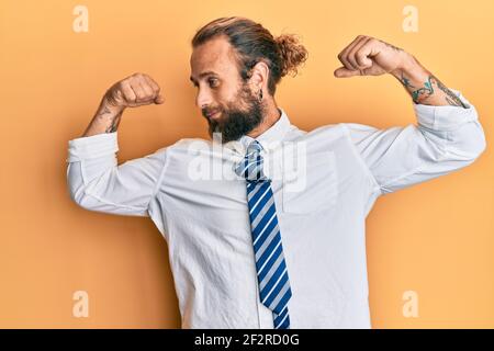 Handsome man with beard and long hair wearing business clothes showing arms muscles smiling proud. fitness concept. Stock Photo