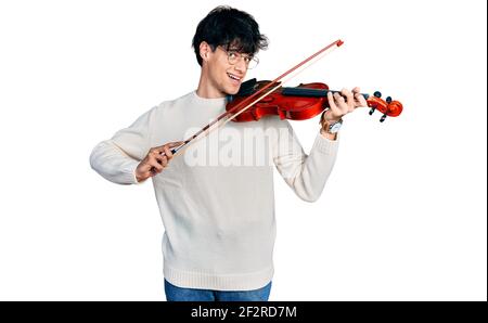 Handsome hipster young man playing violin smiling with a happy and cool smile on face. showing teeth. Stock Photo
