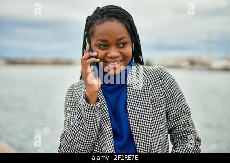 Young african american businesswoman smiling happy talking on the smartphone at the port. Stock Photo