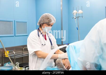 Portrait of an anesthesiologist among a team of doctors monitors instrument readings and patient status Stock Photo