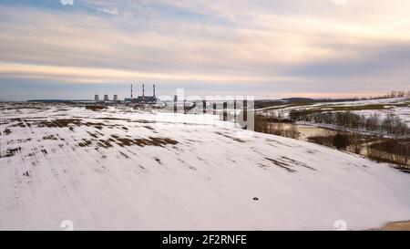 Aerial view of power station in evening light. Early spring urban industrial landscape. Snow melting, Season change. Gas power plant near big city Min Stock Photo