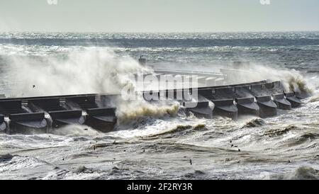 Brighton UK 13th March 2021 - Huge waves crash over Brighton Marina as strong winds batter the south coast again today : Credit Simon Dack / Alamy Live News Stock Photo