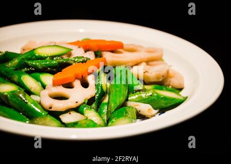 asparagus stir fried with lotus root and carrot serrved in a white plate Stock Photo
