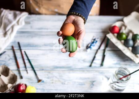 Decorating and painting Easter egg. Woman holding colorful eggs above table Stock Photo