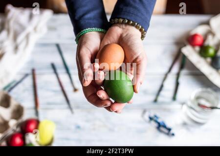 Woman holding colorful eggs in hands above table. Painting and decorating Easter egg Stock Photo