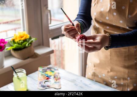Woman painting Easter egg at home. Handmade decoration for holidays. Leisure activity in spring Stock Photo