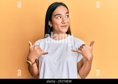 Young asian woman doing shaka sign with hands smiling looking to the side and staring away thinking. Stock Photo