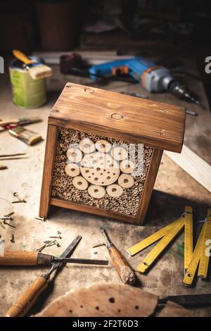 Wooden insect hotel or house on table at workshop. DIY and work tools Stock Photo