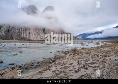 Majestic granite rocks by the surface. Wild arctic landscape of Akshayuk Pass, Baffin Island, Canada on a cloudy, rainy day of arctic summer. Stock Photo