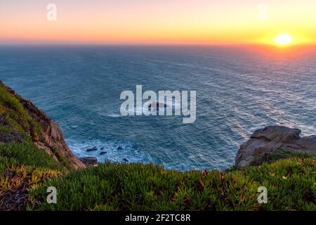 View of the horizon and the setting sun from the cliffs of Cabo da Roca at sunset. The westernmost point of Europe. Sintra, Portugal. Stock Photo