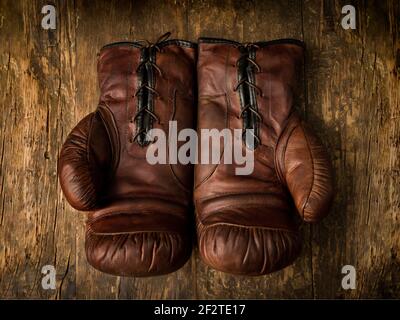 Pair of old brown leather boxing gloves lying on an antique wooden table Stock Photo