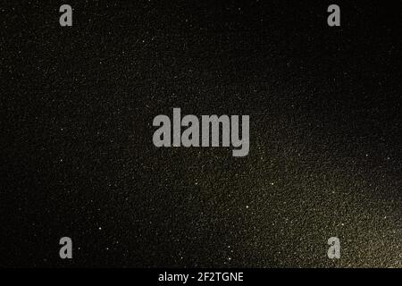 Black texture with micro-relief and glitter. Black glitter texture illuminated from bottom right to top Stock Photo