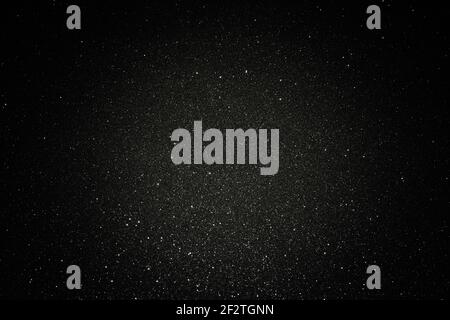 Black texture with micro-relief and glitter. Black glitter texture with illuminated center Stock Photo