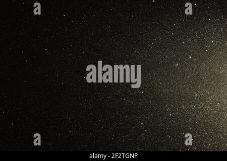 Black texture with micro-relief and glitter. Black glitter texture illuminated from right Stock Photo