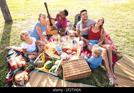High angle top view of happy family having fun with kids at pic nic barbecue party - Multiracial love concept with mixed race people playing together Stock Photo
