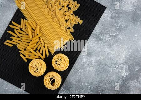 Various dry pasta on black bamboo sheet Stock Photo