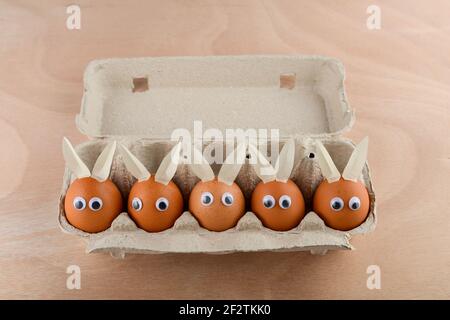 Easter eggs with eyes and rabbit ears in an egg container. Happy Easter concept. Stock Photo