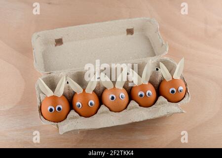 Easter eggs with eyes and rabbit ears in an egg container. Happy Easter concept. Stock Photo
