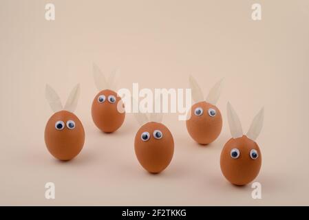 Easter Eggs with eyes and Rabbit ears on beige background. Copy space. Happy Easter concept. Stock Photo