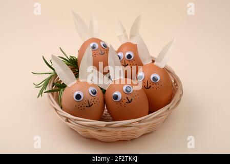 Easter eggs with eyes and rabbit ears in an wicker basket. Happy Easter concept. Stock Photo