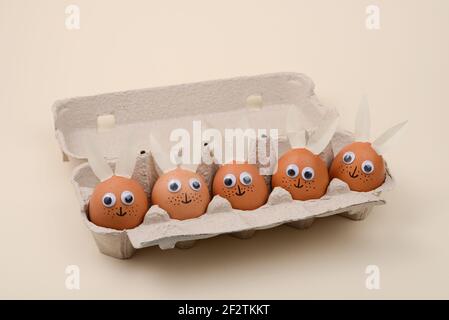 Easter eggs with eyes and rabbit ears in an egg container. Happy Easter concept. Stock Photo