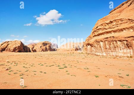 Rocky massifs on red sand desert, bright blue sky in background - typical scenery in Wadi Rum, Jordan Stock Photo