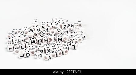Heap of small white cube beads with various letters scattered on board, space for text right side Stock Photo