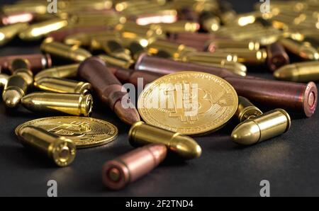 Bronze and brass gun bullets scattered on black table, golden bitcoin coins near - illegal use of cryptocurrency to purchase weapon concept Stock Photo