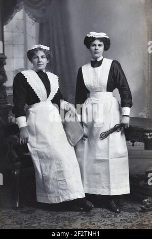 Full-length Portrait of Two Maids, Housemaids, Victorian Maids or Edwardian Maids Dressed in Aprons & Maid Uniforms Rhyl Wales UK c1900-1920 Stock Photo