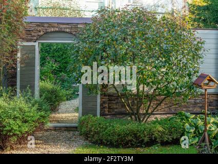 element of landscape design - mirror in the wall of garden - creating the illusion of transition into another space don't existing. (Russian dacha - Stock Photo