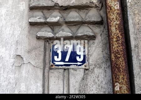 Number 379 number of houses apartments streets. White number of blue metal plate house number three hundred and seventy-nine (379) on the rough wall Stock Photo